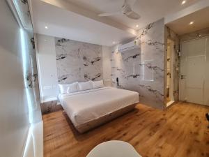 Lotus Rooms@Rockbeach في بونديتْشيري: غرفة نوم بسرير أبيض وجدار من الرخام