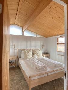 een groot bed in een kamer met een houten plafond bij Hestaland Horse Farm Cottage in Borgarnes