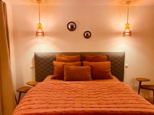 een slaapkamer met een bed met oranje lakens en verlichting bij M&S - Maison FÉRAUD in Saint-Rémy-de-Provence