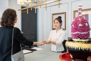 a woman shaking hands with a woman standing next to a cake at Luangprabang D'or Boutique Hotel in Luang Prabang