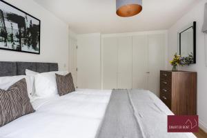 um quarto com uma cama branca e uma cómoda em madeira em Englefield Green - Modern 2 bedroom Apartment em Englefield Green