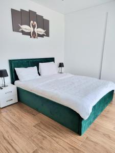 um quarto com uma grande cama verde e 2 candeeiros em Horizon-Endless Summer Apartaments em Mamaia Nord – Năvodari