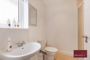 a white bathroom with a toilet and a sink at Bracknell - 4 Bedroom House - With Driveway, Garden & Garage in Bracknell +10 photos