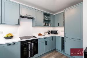 a kitchen with blue cabinets and white counter tops at Woking - 2 Bed Eco-Friendly Home in Horsell