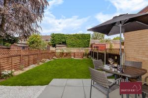a backyard with a table and an umbrella at Woking - 2 Bed Eco-Friendly Home in Horsell