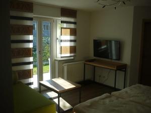 Cette chambre comprend une télévision, un lit et une table. dans l'établissement Ferienwohnungen beim Hotel zur Post, Erlau, à Erlau