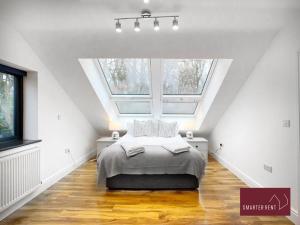 a attic bedroom with a bed and a large window at Shepperton - 3 Bedroom Home in Walton-on-Thames