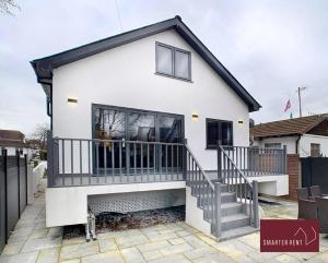 a white house with a black roof and stairs at Shepperton - 3 Bedroom Home in Walton-on-Thames