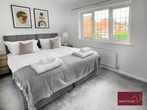 a bedroom with a large bed with two towels on it at Knaphill - 2 Bedroom Terrace House - With Garden in Brookwood