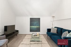 a living room with a blue couch and a tv at Richmond - 2 Bedroom Duplex Apartment in Richmond upon Thames