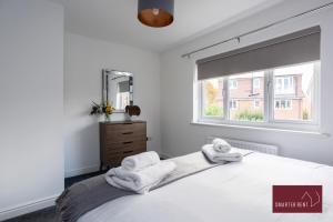 una camera bianca con asciugamani su un letto con finestra di Jennett's Park, Bracknell - 2 Bedroom Home - Garden & Parking a Bracknell