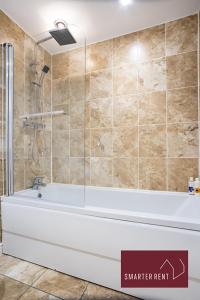 a bathroom with a bath tub and a shower at Jennett's Park, Bracknell - 2 Bedroom Home - Garden & Parking in Bracknell
