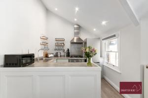 a kitchen with white walls and a counter with a microwave at Richmond - 2 Bedroom Duplex Apartment in Richmond upon Thames