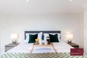 a bedroom with a large bed with green pillows at Richmond - 2 Bedroom Duplex Apartment in Richmond upon Thames