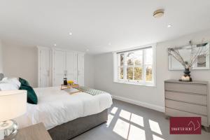 een witte slaapkamer met een bed en een raam bij Richmond - 2 Bedroom Duplex Apartment in Richmond upon Thames