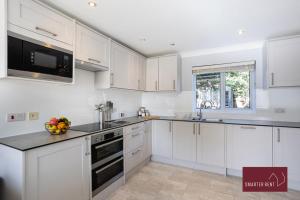 una cocina con armarios blancos y un bol de fruta en la barra en Wimbledon - 4 Bedroom Home With Parking, Garden & Office, en Londres