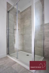 a shower with a glass door in a bathroom at Wimbledon - 4 Bedroom Home With Parking, Garden & Office in London