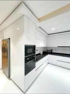 a white kitchen with black appliances and white cabinets at Orion_apartments in Lagos
