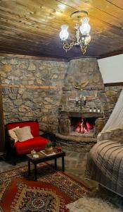 a living room with a stone fireplace and a red couch at Το Πέτρινο Σπιτάκι in Tríkala