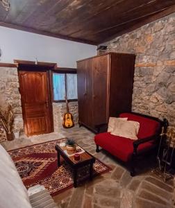 a living room with a red couch and a guitar at Το Πέτρινο Σπιτάκι in Tríkala