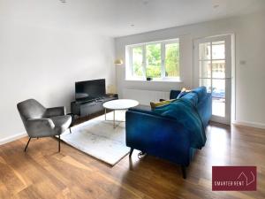 Guildford - 2 Bedroom House في West Clandon: غرفة معيشة مع أريكة زرقاء وكرسي