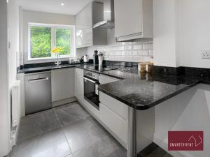 a kitchen with white cabinets and a black counter top at Guildford - 2 Bedroom House - Parking in West Clandon