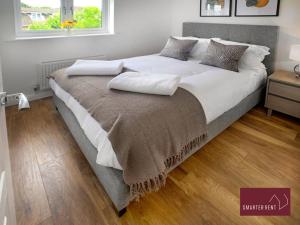 een groot bed met witte lakens en kussens erop bij Guildford - 2 Bedroom House in West Clandon