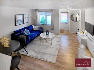 a living room with a blue couch and a table at Lightwater - One Bedroom House - With Parking in Bagshot