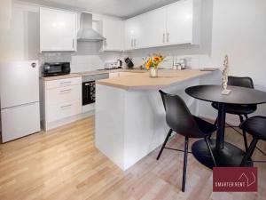 a kitchen with white cabinets and a table and chairs at Lightwater - One Bedroom House - With Parking in Bagshot