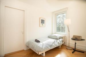 Una habitación blanca con una cama y una ventana. en Spacious apartment next to park with free BaselCard, en Basilea 2 fotos más
