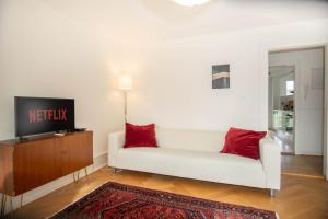 a living room with a white couch and a tv at Spacious apartment next to park with free BaselCard in Basel