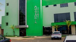 a green and white building with a car parked in front at Amazônia Palacce Hotel in Marabá