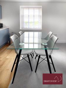 a glass table with four white chairs in a room at Eton, Windsor - 2 Bedroom Second Floor Apartment - With Parking in Eton