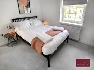 a bedroom with a bed with white sheets and a window at Eton, Windsor - 2 Bedroom Second Floor Apartment - With Parking in Eton