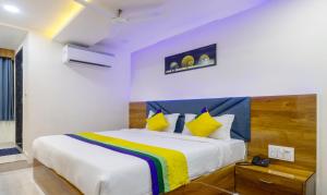 a bedroom with a large white bed with yellow and blue pillows at Itsy By Treebo - Signature, Nehru Nagar in Ahmedabad