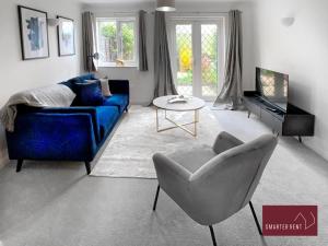 BrookwoodにあるKnaphill, Woking - 2 Bedroom House - Garden and Parkingのリビングルーム(青いソファ、椅子付)