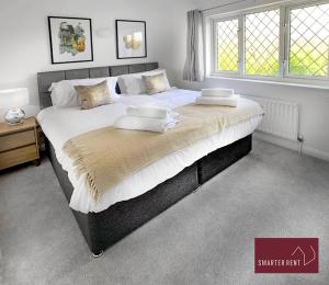 a large bed with white sheets and pillows on it at Knaphill, Woking - 2 Bedroom House - Garden and Parking in Brookwood