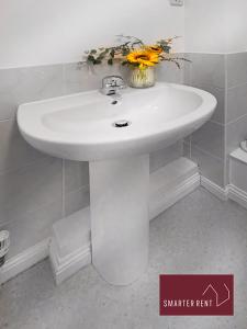 a white sink in a bathroom with flowers on it at Knaphill, Woking - 2 Bedroom House - Garden and Parking in Brookwood