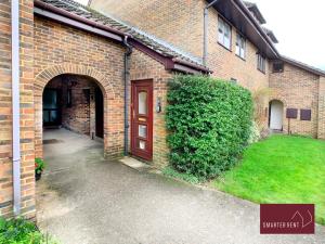 a brick building with a red door and a yard at Wokingham - 2 Bedroom Maisonette - With Parking in Wokingham