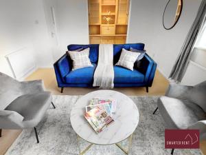 Wokingham - 2 Bedroom Maisonette - With Parking في وكينغهام: غرفة معيشة مع أريكة زرقاء وطاولة
