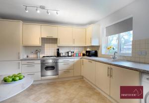 Wokingham - 2 Bedroom Maisonette - With Parking في وكينغهام: مطبخ مع خزائن بيضاء ووعاء من التفاح الأخضر
