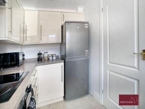 a kitchen with a stainless steel refrigerator and white cabinets at Twyford - Modern 2 Bedroom House - Garden and Parking in Twyford