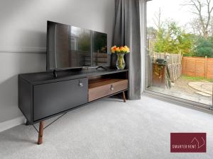 uma televisão numa cómoda num quarto com uma janela em Maidenhead- 3 Bedroom House With Garden em Maidenhead
