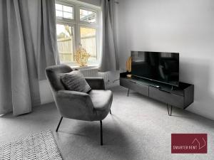 a living room with a chair and a television at Bracknell - 2 Bedroom House With Garden and Parking in Easthampstead