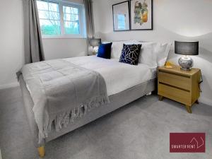 a bedroom with a large bed and a night stand at Bracknell - 2 Bedroom House With Garden and Parking in Easthampstead