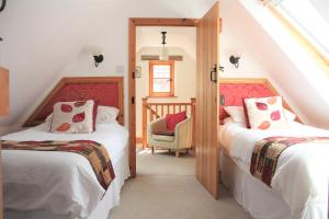 a attic bedroom with two beds and a chair at Woodman's Farm in Norwich