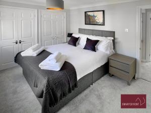 a bedroom with a large bed with towels on it at Maidenhead - Gated 2 Bedroom Flat, Close To Train Station in Maidenhead