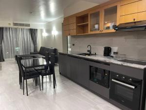 a kitchen with black appliances and a table and chairs at Spacious 2BD, 1min BTS Central Ladprao Jodd Fair Night Market in Bangkok