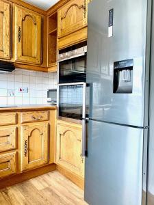 a stainless steel refrigerator in a kitchen with wooden cabinets at Stratford upon Avon: 2 bed town centre apartment, parking for one car in Stratford-upon-Avon