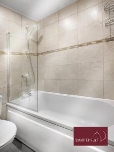 a bathroom with a bath tub and a toilet at Farnborough - Modern 2 Bedroom House in Blackwater